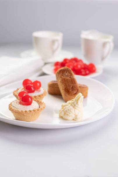 Dessert de noisettes sucrées avec des doigts d'amande et deux gâteaux de panier et tasse de café et cruche de lait à l'arrière-plan - Photo, image