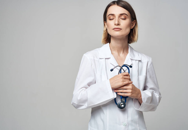 Un médecin professionnel en blouse médicale tient un stéthoscope dans sa main - Photo, image