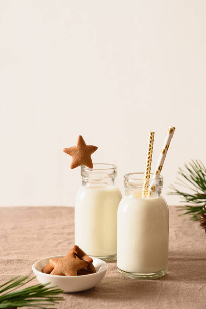 Homemade cookies in shape of star and milk for Santa Claus and christmas tree on table. Close up. - Fotó, kép