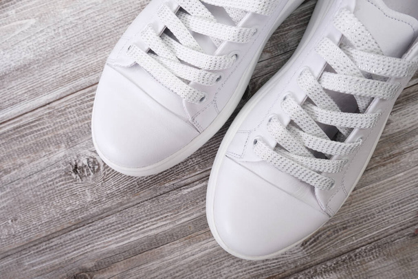White leather casual sneakers on wooden background - Photo, image