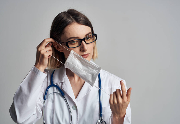 Professionele verpleegkundige in een medisch gewaad en masker op het gezicht van een infectielaboratorium - Foto, afbeelding