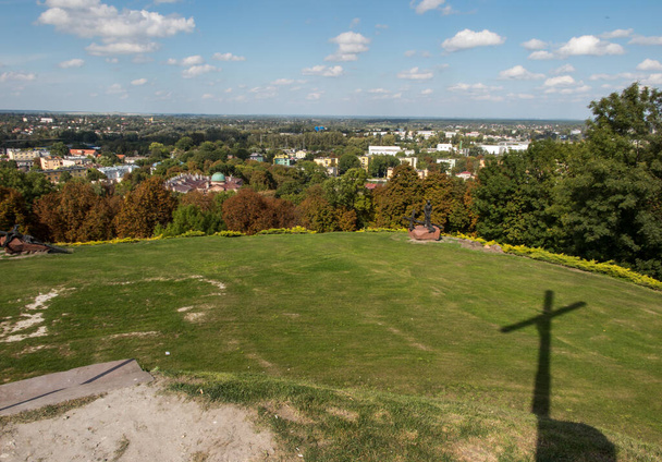 The Sanctuary of Our Lady in Chelm in Poland with the area of the Way of the Cross and two visible stations and the shadow of the cross In the background, the panorama of Chelm and the sky with clouds - Photo, Image