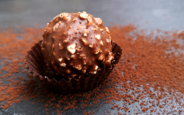 Νόστιμο σοκολάτα καραμέλα μπάλα με γέμιση και ξηρούς καρπούς σε σκούρο φόντο - Φωτογραφία, εικόνα