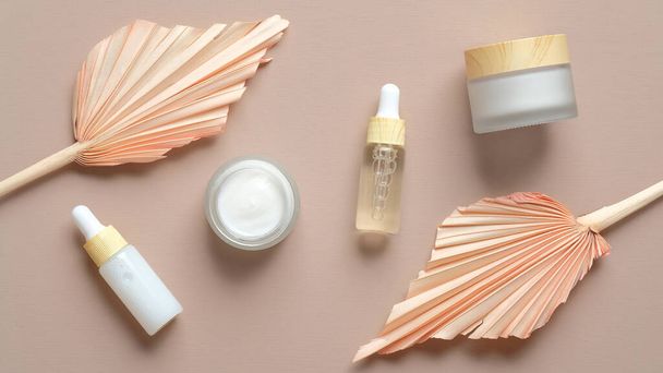 Natural skincare beauty products and dry leaves on pastel beige background. Organic cosmetics set. - Foto, Imagen