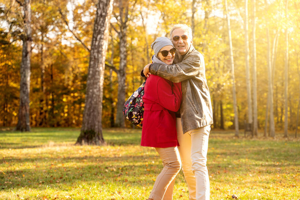 Romantic happy senior couple hugging in beautiful sunny autumn city park. Relationship and people concept  - Zdjęcie, obraz
