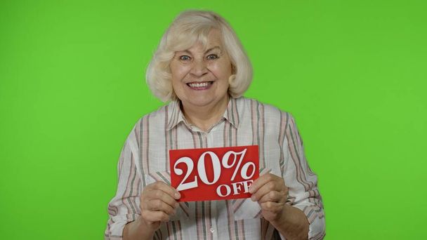 Seniorská babička ukazující 20% slevu z nápisu, radostná sleva, nízké ceny - Fotografie, Obrázek