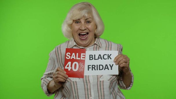 Abuela mayor mostrando Viernes Negro, 40 por ciento de descuento en banners de publicidad de descuento. Clave de croma - Foto, imagen