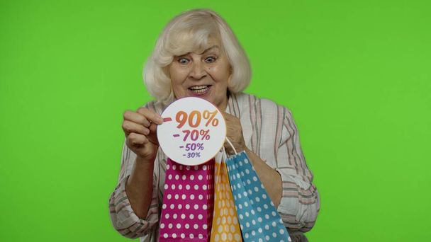 Starsza babcia pokazuje sprzedaż procent zniżki napis reklamowy z torby na zakupy - Zdjęcie, obraz