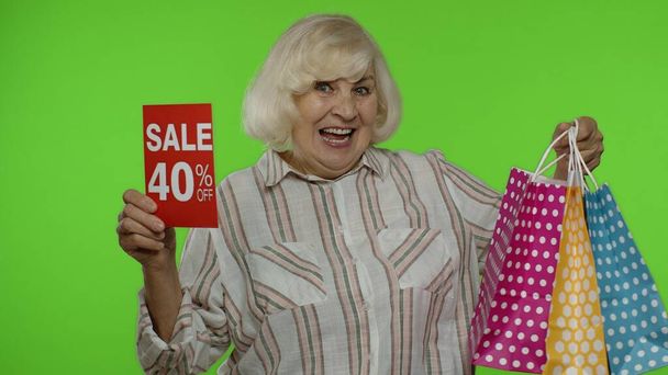 Wesoła babcia z torbami na zakupy pokazuje sprzedaż 40 procent off banner text advertisement - Zdjęcie, obraz