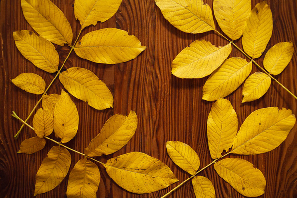 Желтые осенние листья на деревянном фоне с пространством для текста. Осенний фон с осенними листьями. - Фото, изображение