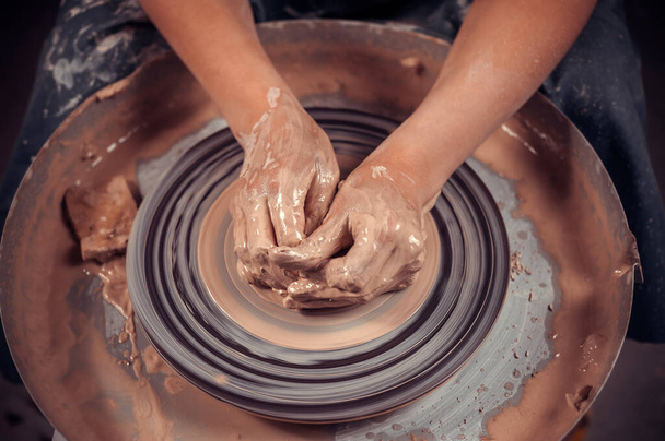 Hands of the master potter and vase of clay on the potters wheel close-up. Master crock. Twisted potters wheel. - Photo, Image