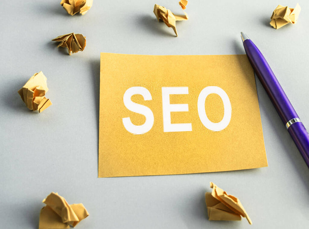SEO- search engine optimization, words on yellow square paper, crumpled sheets and a pen are scattered nearby. Idea, vision, strategy, analysis, key words and concept of the content - Fotó, kép