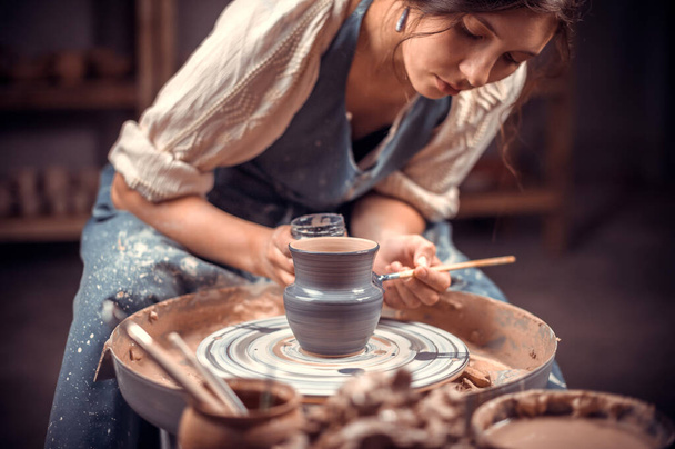 Elegante alfarero artesano muestra cómo trabajar con la arcilla y la rueda de cerámica. Productos hechos a mano. - Foto, Imagen
