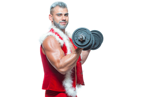 Sexy Santa Claus. Bodybuilder young handsome santa clause smile holds a dumbbells and shows off abs cubes at New Years eve and Christmas winter holiday white background. - Fotoğraf, Görsel