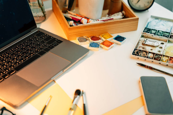Top view - artist working desk met kleurenschilderapparatuur en papieren mock up. - Foto, afbeelding