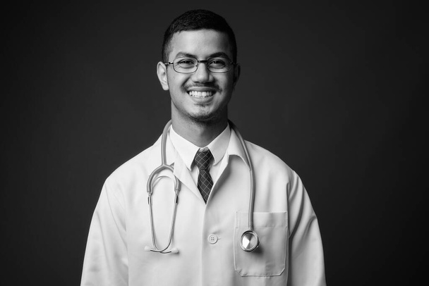 Fiatal multi etnikai ázsiai férfi orvos szürke háttér - Fotó, kép