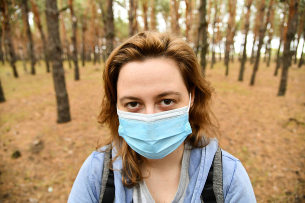 Giovane donna che indossa una maschera protettiva in un parco. Concetto di quarantena, anti coronavirus, virus e influenza. - Foto, immagini