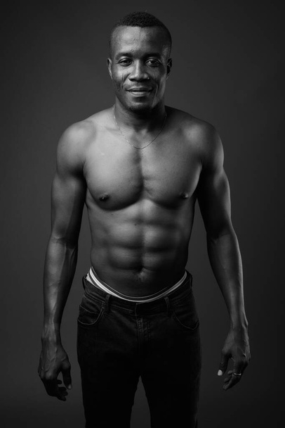 Молодой африканский мужчина без рубашки на сером фоне - Фото, изображение