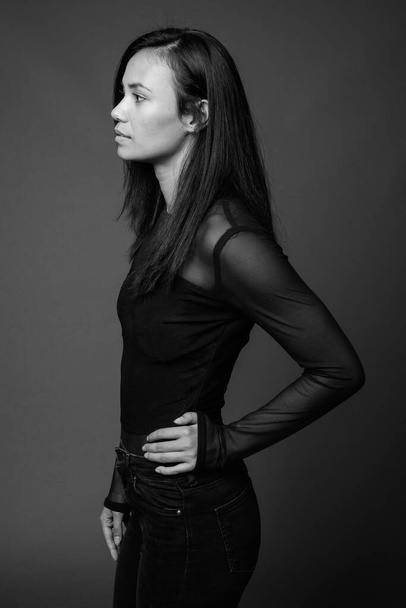 Studio shot of young Asian woman against gray background - Zdjęcie, obraz
