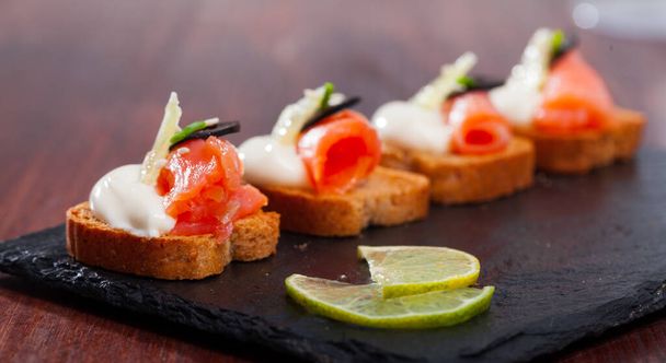 Canapes with salmon and black olives on cream sauce - Foto, afbeelding
