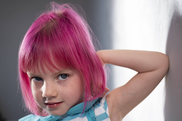 Niña con el pelo rosa se levanta contra la pared en la habitación - Foto, imagen