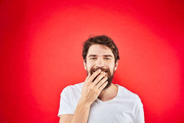 Бородатый человек весело эмоции образ жизни обрезанный вид белый футболка красный фон - Фото, изображение