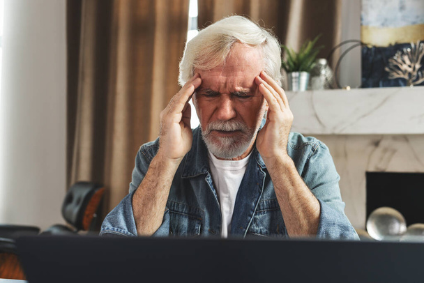 Elderly man holding his head experiencing headache and stress due to pressure - Foto, Bild