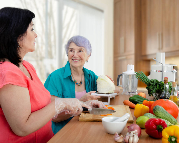Współczujący sąsiad lub wynajęta aktorka i samotna staruszka przygotowują razem danie warzywne. Starsza pani jest bardzo zadowolona.. - Zdjęcie, obraz