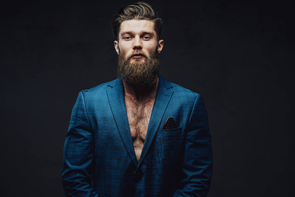 Serious bearded guy posing in suite in dark background - Photo, Image