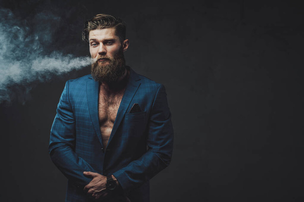 Elegance styled man with beard smoking in dark background - Photo, Image