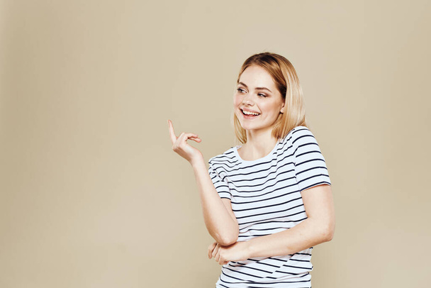 Cheerful woman striped t-shirt studio beige background lifestyle emotions - 写真・画像