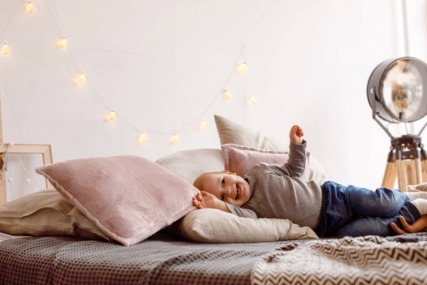 Cheerful little kid having fun on bed - Foto, afbeelding