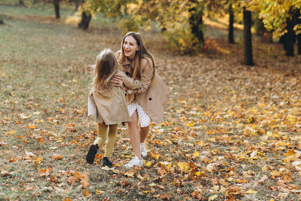 Happy mother and her beautiful daughter have fun and walk in the autumn park. - Foto, immagini