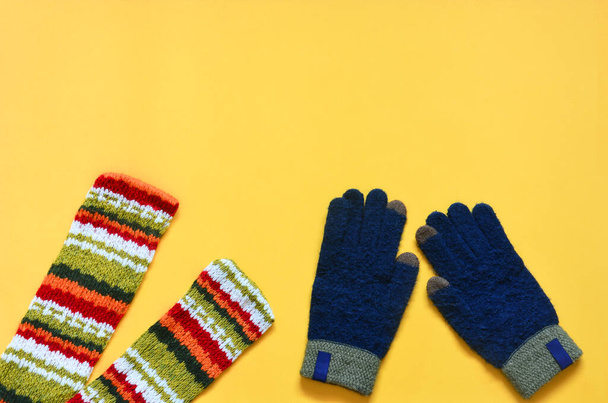 вид сверху на красочный трикотажный шарф и голубые перчатки на желтом фоне, пространство для копирования, плоский узор - Фото, изображение