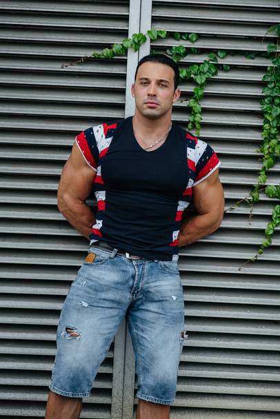 A sporty guy stands near a gray wall. Lifestyle - Φωτογραφία, εικόνα