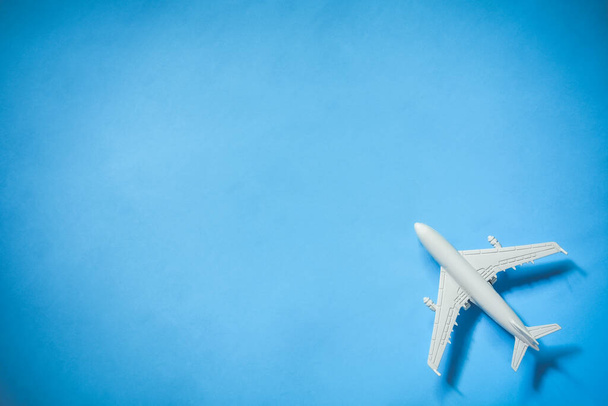bovenaanzicht van wit speelgoed vliegtuig model over blauwe kleur achtergrond met kopieerruimte, concept van reizen - Foto, afbeelding