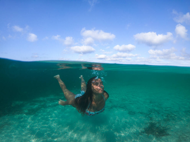 Женщина ныряет в море. Вид на уровень воды, камера 50% под водой, фото с подводным куполом. - Фото, изображение