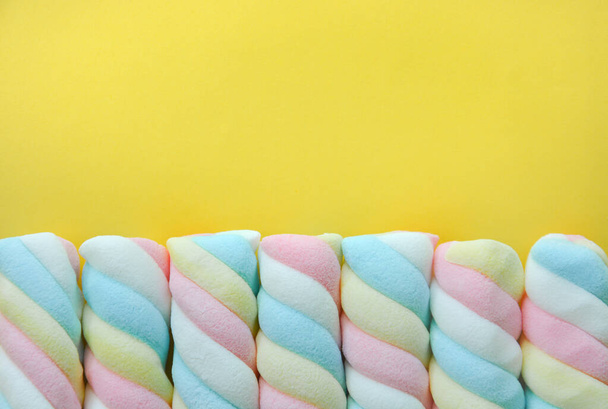 vista superior de marshmallow cor pastel torcido no fundo amarelo com espaço de cópia, flat lay - Foto, Imagem