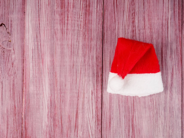 pequeño sombrero de Santa Claus sobre un fondo de madera, símbolo de la Navidad, minimalismo. - Foto, imagen