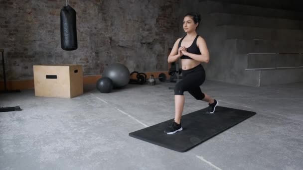 Jeune femme sportive faisant des squats pour les fessiers dans l'entraînement de fente latérale. Fille de remise en forme athlétique faisant des exercices de conditionnement physique aérobie pour butin dans la salle de gym. Concept de fitness et bien-être. - Séquence, vidéo
