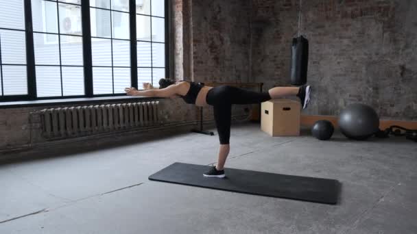 Side ViewEen jonge Indiase vrouw is betrokken bij een training, Meisje in een zwarte top en Leggings doen Leg Stretches, doen Workout in de Gym - Video