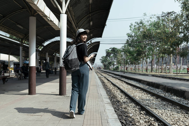 asiático tailandés mochilero mujer viajero caminar un espera en ferrocarril plataforma. - Foto, Imagen