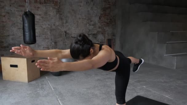 Close - up of a Sporty Young Indian Woman in a Black Top and Leggings Κάνοντας μια άσκηση ισορροπίας, κάνοντας προπόνηση στο γυμναστήριο, η κάμερα προχωρά μπροστά - Πλάνα, βίντεο