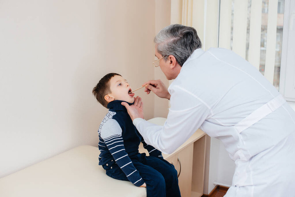 A young boy is listened to and treated by an experienced doctor in a modern clinic. A virus, and an epidemic - Фото, зображення