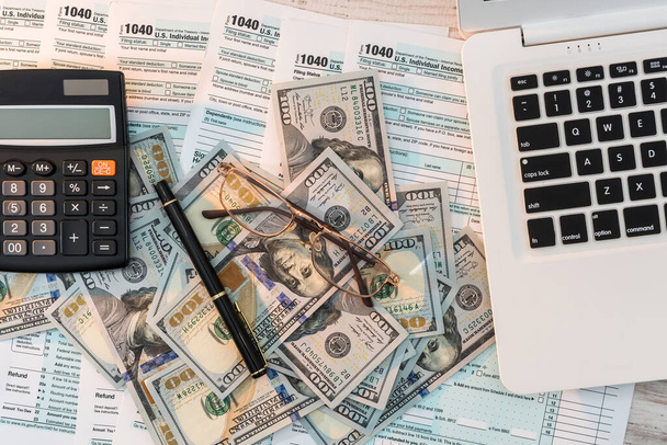 us 1040 tax form with pen, dollar and laptop at office. tax time. accounting concept - 写真・画像