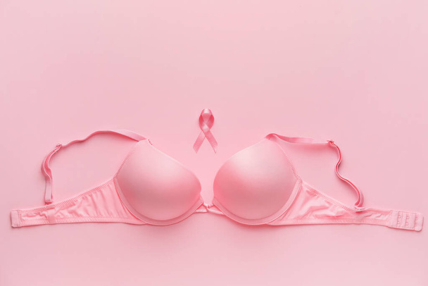 Pink ribbon and bra on color background. Breast cancer awareness concept - Photo, Image