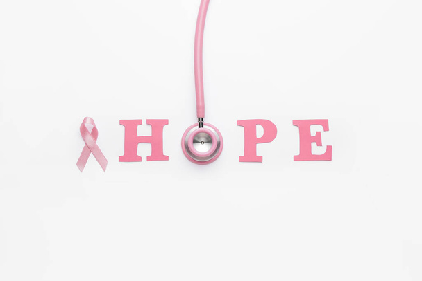 Pink ribbon, stethoscope and word HOPE on white background. Breast cancer awareness concept - Photo, Image
