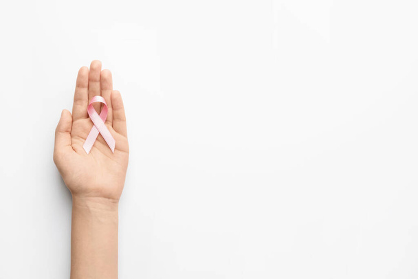 Жіноча рука з рожевою стрічкою на білому тлі. Концепція обізнаності про рак молочної залози
 - Фото, зображення