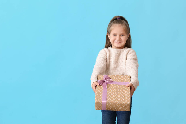 Cute little girl with gift on color background - Fotoğraf, Görsel