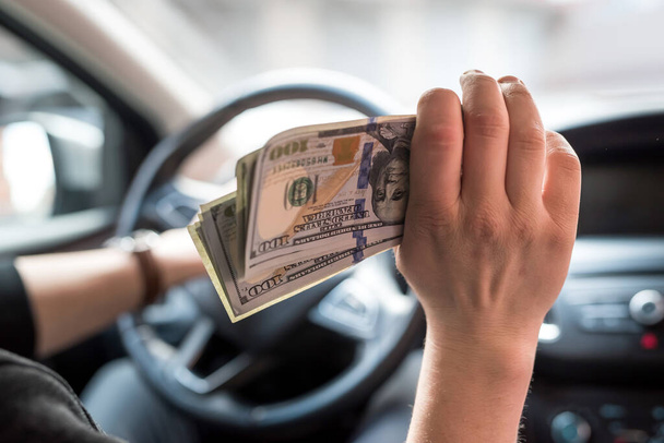 businessman pays for a product or service, gives dollars while sitting in the car. finance concept - Photo, Image